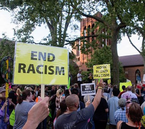 crowd with someone holding a sign that says "end racism"