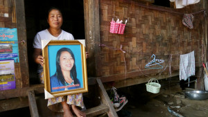 Lu Bu - Mother of Hkawn Nan Tsin Woman in doorway of woven wood house, holding framed picture of her murdered daughter