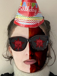 A picture of the birthday girl in a birthday hat not looking too happy.