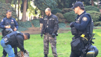 Jay Bishop's bag being searched by Fed. Protective Services Dist. Cmdr. Luis Lopez (Jasmin Moneymaker)